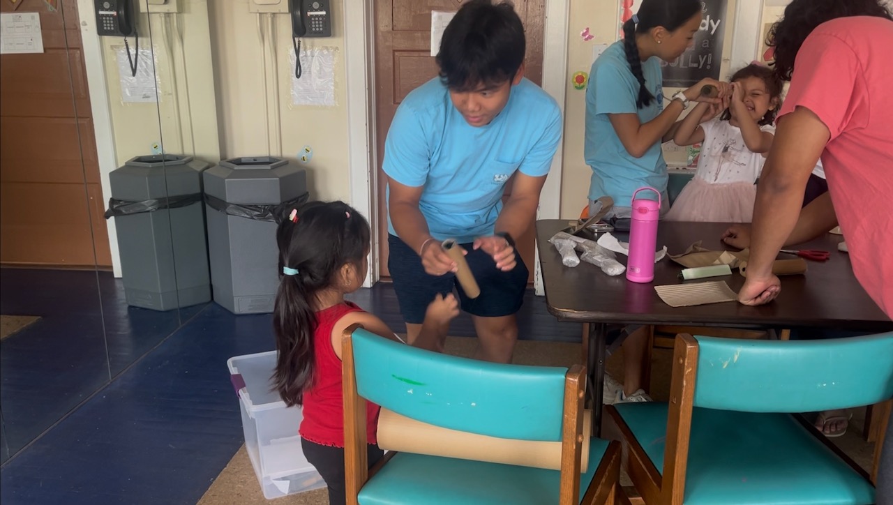 Thomas helping a young child with a hands-on art project at Don Bosco Community Center.