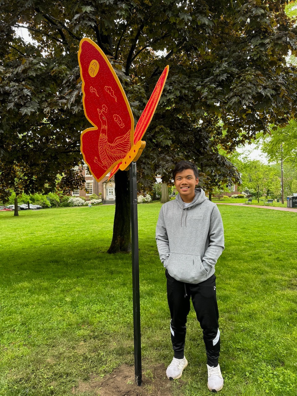 Thomas standing beside the red and gold butterfly sculpture Golden Serenity.