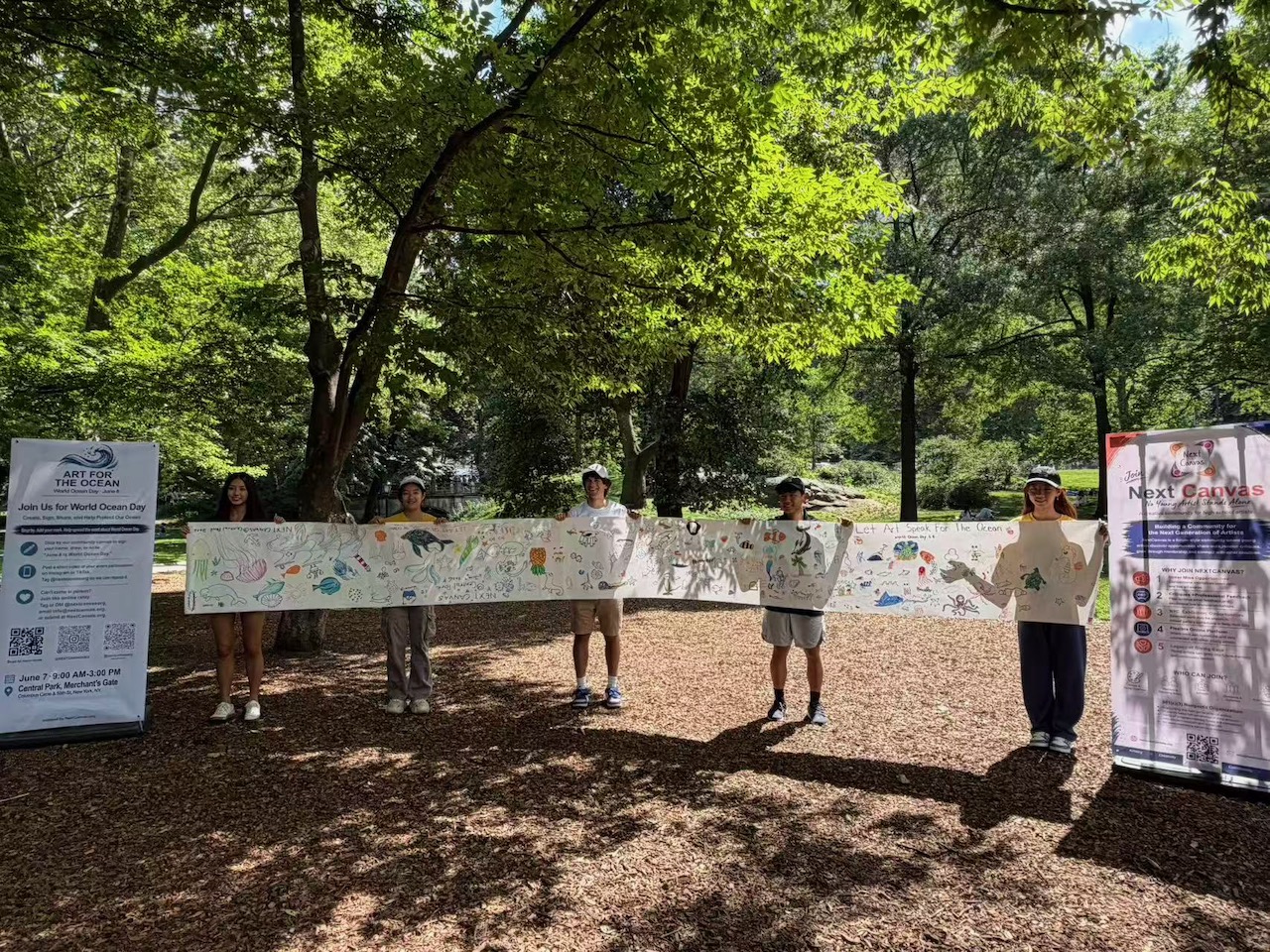 NextCanvas volunteers holding a long scroll of ocean-themed community drawings in Central Park.