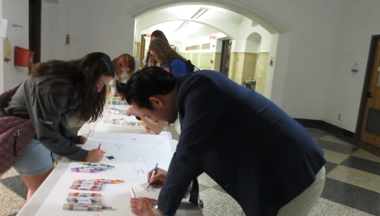 Rye High School students contributing drawings to a shared NextCanvas paper scroll.